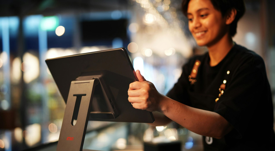 Friendly barista using a tablet for efficient service at a modern Mexican café.