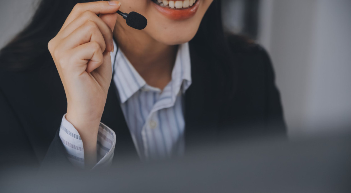 Woman in a blazer smiling while using a microphone during a professional video call.