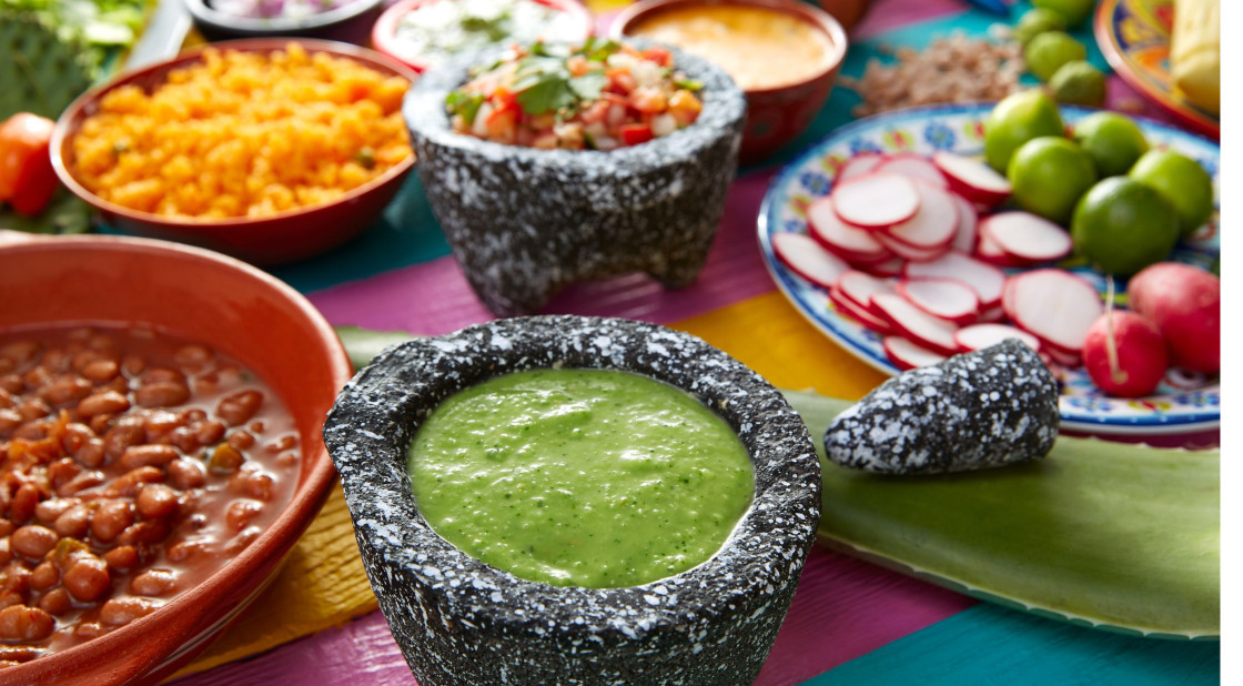 Vibrant traditional Mexican dishes with salsa, rice, beans, and fresh ingredients on a colorful table.